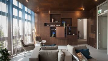 A modern lobby with a sofa, chairs, and a wall-mounted shelf with decorative items.