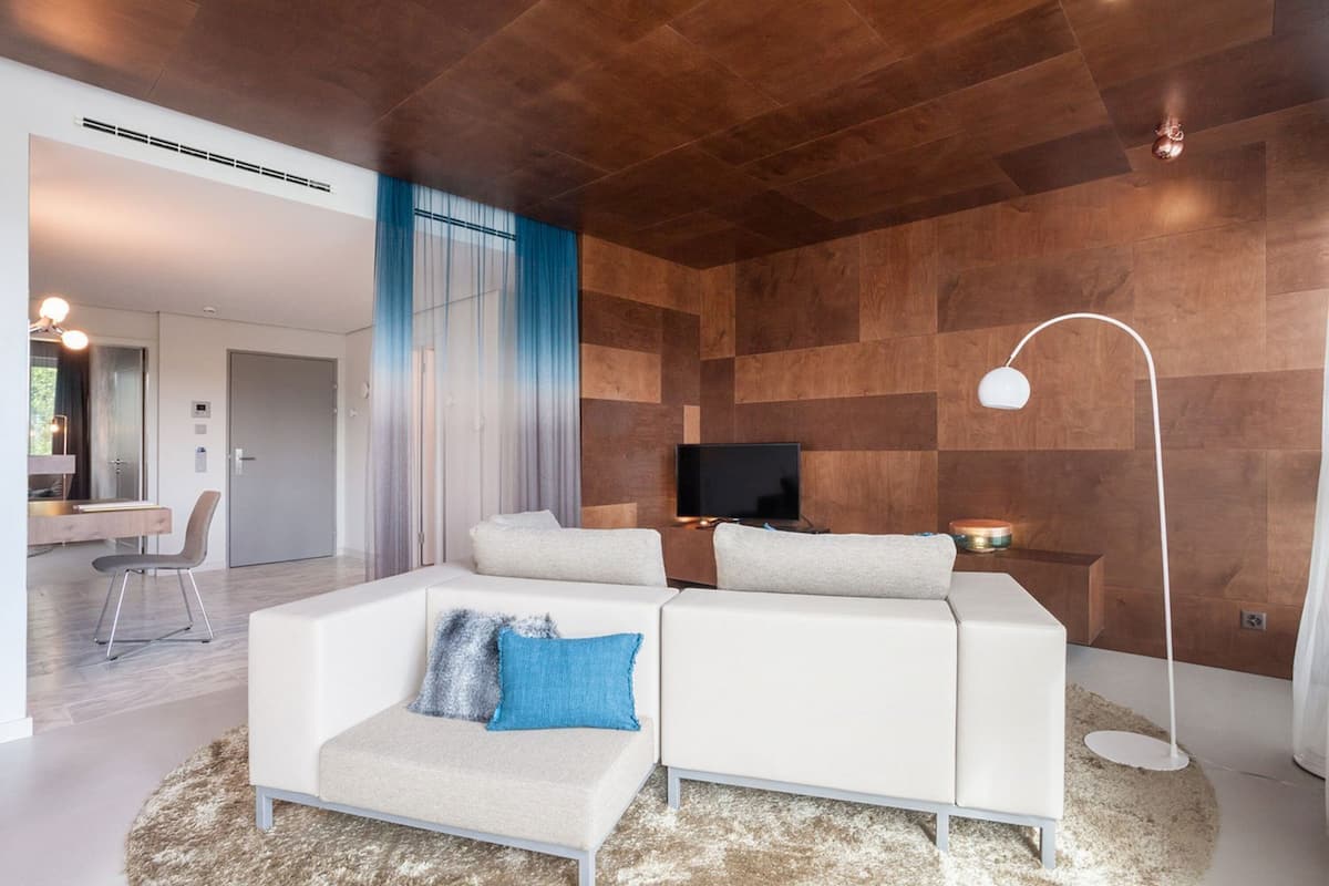 A modern living room with a white sofa, a flat-screen TV, and a wooden accent wall.