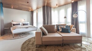 Un dormitorio moderno con cama, sofá y un ventanal con cortinas.