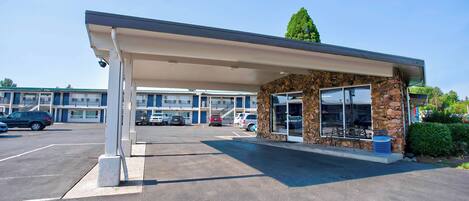 A gas station with a covered canopy, a stone facade, and a parking lot with several cars.
