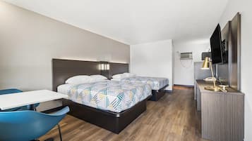A hotel room with a bed, a desk, a chair, a TV, and a minibar.
