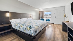 Una habitación de hotel moderna con una cama grande, un escritorio y un balcón con vistas.