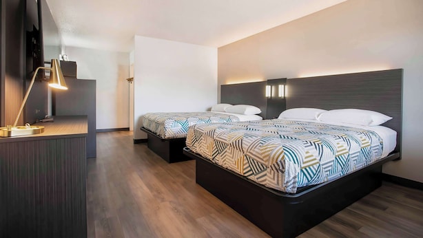 Una habitación de hotel moderna con dos camas, un escritorio y una lámpara de escritorio.