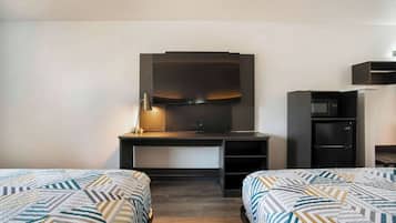 A hotel room with two beds, a desk with a flat-screen TV, a microwave, and a small refrigerator.