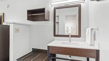 Un baño moderno con tocador de madera, un espejo, toallero y una pequeña estantería.