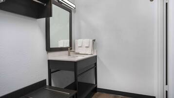 A modern bathroom with a dark vanity, a mirror, and a white sink.