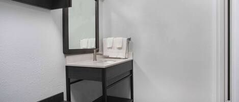 A modern bathroom with a dark vanity, a mirror, and a white sink.