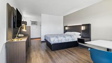 A modern hotel room with a bed, a desk, a chair, and a TV.