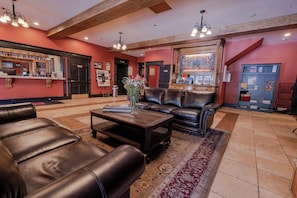 A lobby with leather sofas, a coffee table, a reception desk, and a mural on the wall.