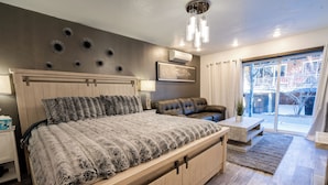 Un dormitorio moderno con una cama grande, un área de descanso y vistas al exterior.
