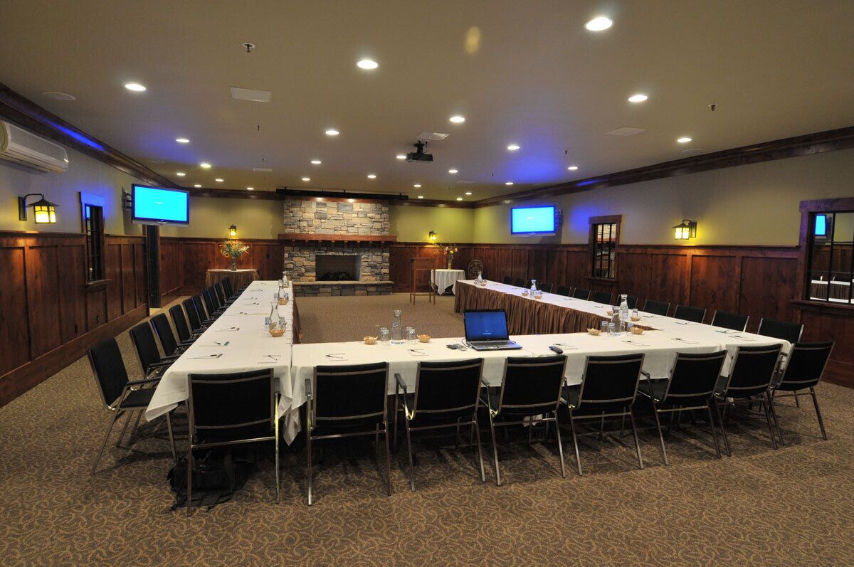 A conference room with a long table, chairs, a fireplace, and two televisions.