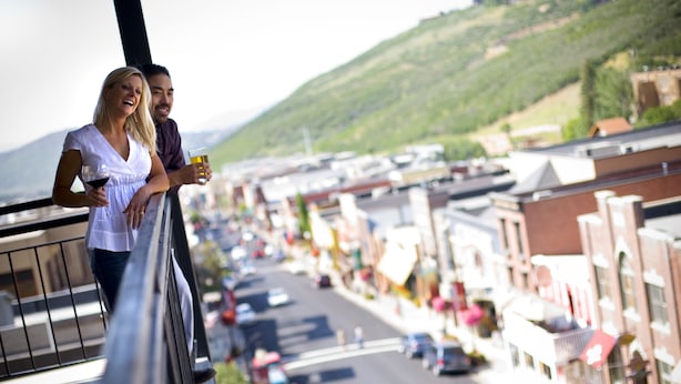 Un balcón con vista a una calle con edificios y coches estacionados.
