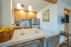 A kitchen with wooden cabinets, a marble countertop, and a dining area with a table and chairs.