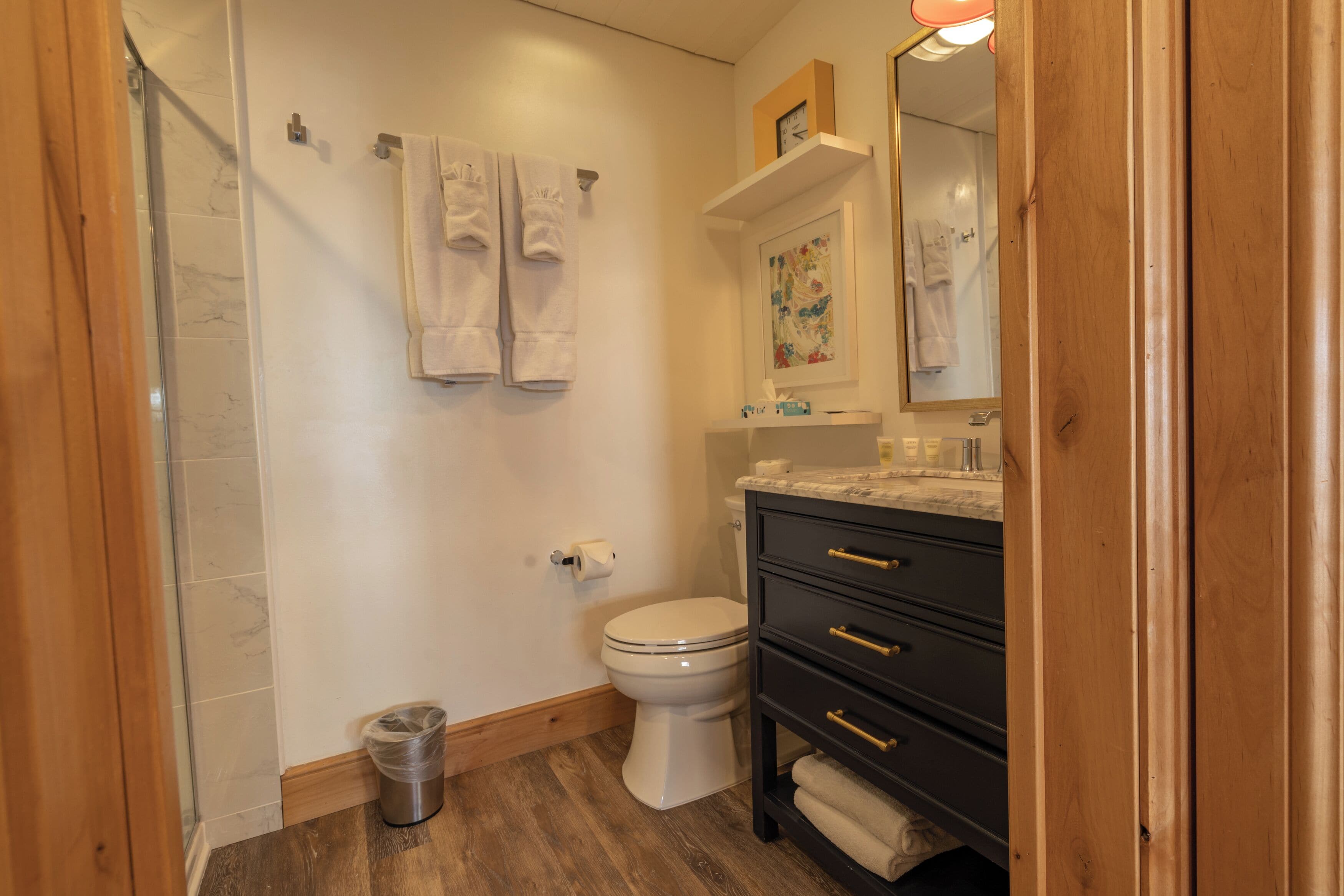 A bathroom with a toilet, a sink, a mirror, and a shower.