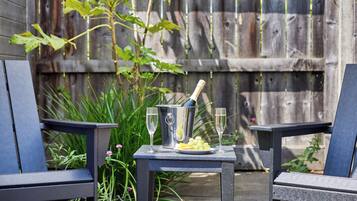 A patio with two chairs, a small table, and a bottle of champagne.