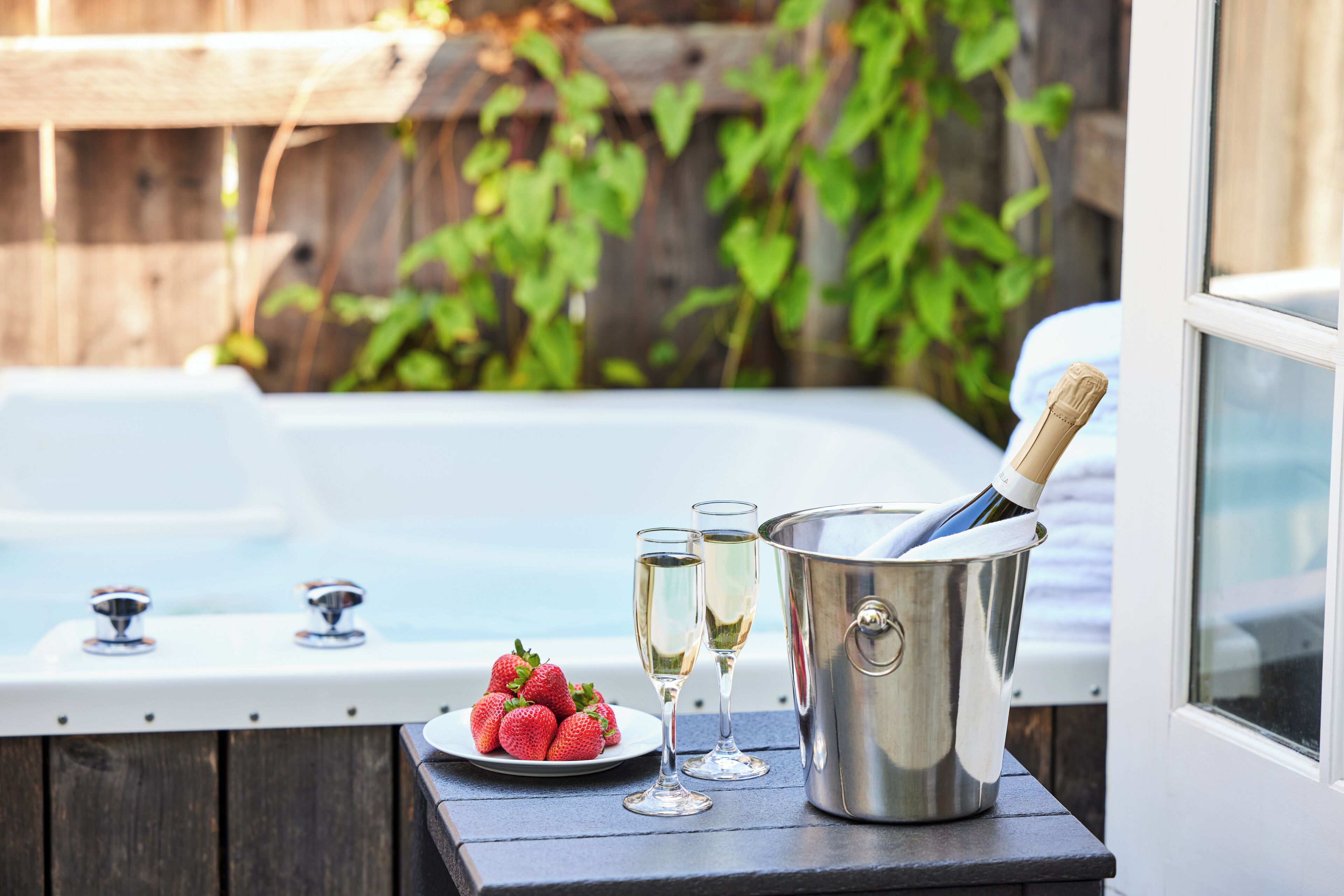Ein Whirlpool mit Champagner und Erdbeeren auf einem Holztisch.