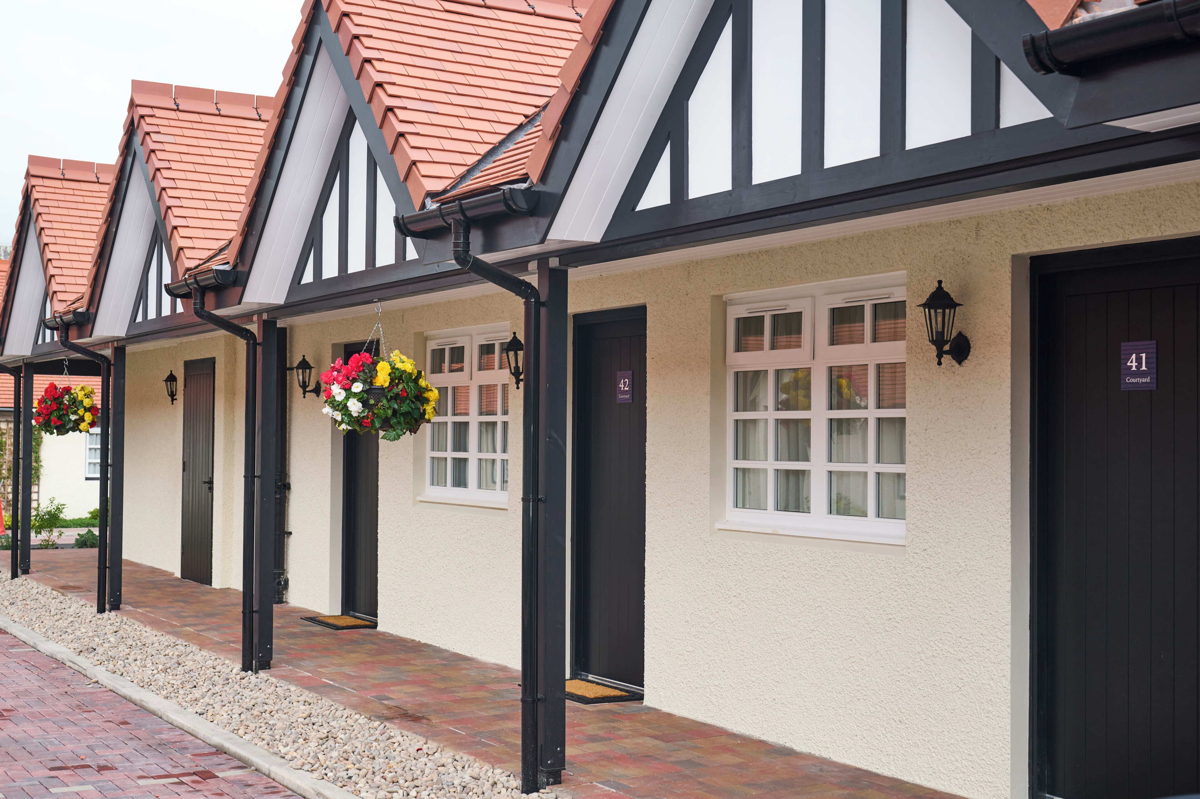 A row of traditional-style buildings with black-framed windows and a tiled roof.