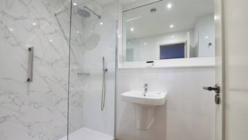 A modern bathroom with a glass-enclosed shower, a white sink, and a mirror above the sink.
