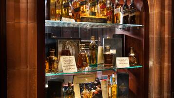 Exhibición de diversas botellas de licor en una vitrina con etiquetas y precios.
