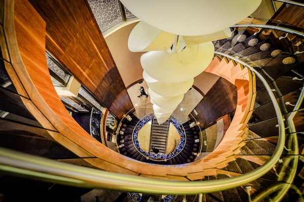 A spiral staircase with a central column and a decorative light fixture. - Osprey Hotel (Naas)