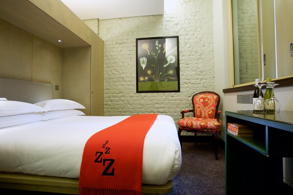 Une chambre d’hôtel avec un lit, une chaise, un bureau et une œuvre d’art encadrée au mur.