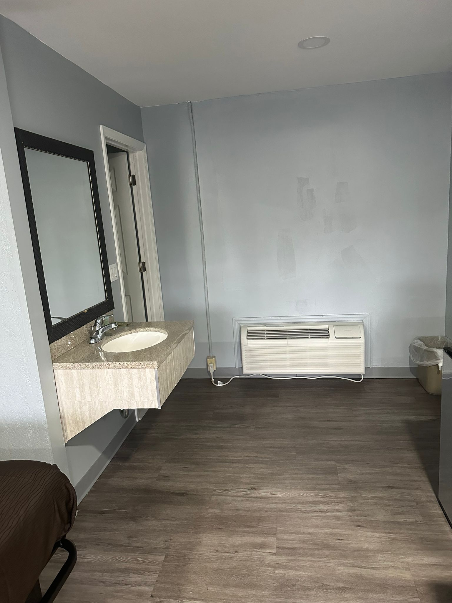 A bathroom with a double sink, a mirror, a heater, and a trash bin.
