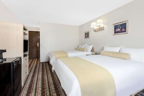 Una camera d'albergo con due letti, una scrivania, una sedia, una lampada e un quadro appeso al muro.