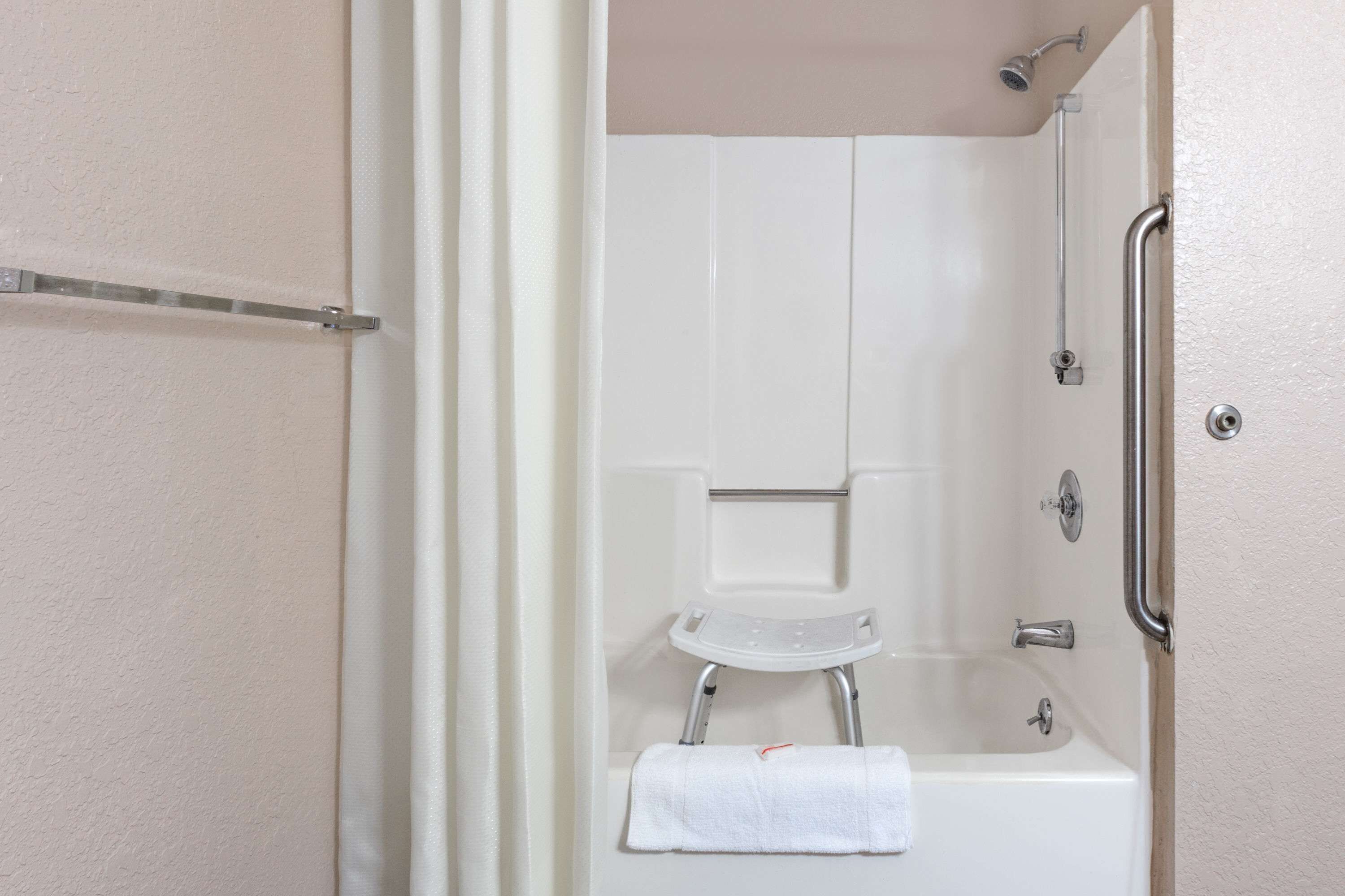 A bathroom with a white bathtub, a shower, and a small step stool.