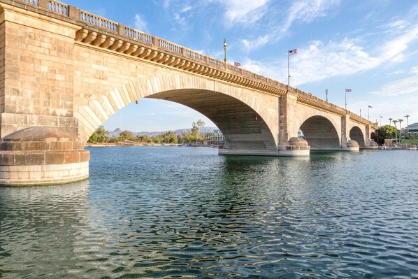 Un puente de piedra con múltiples arcos sobre el agua, con barandillas y banderas.
