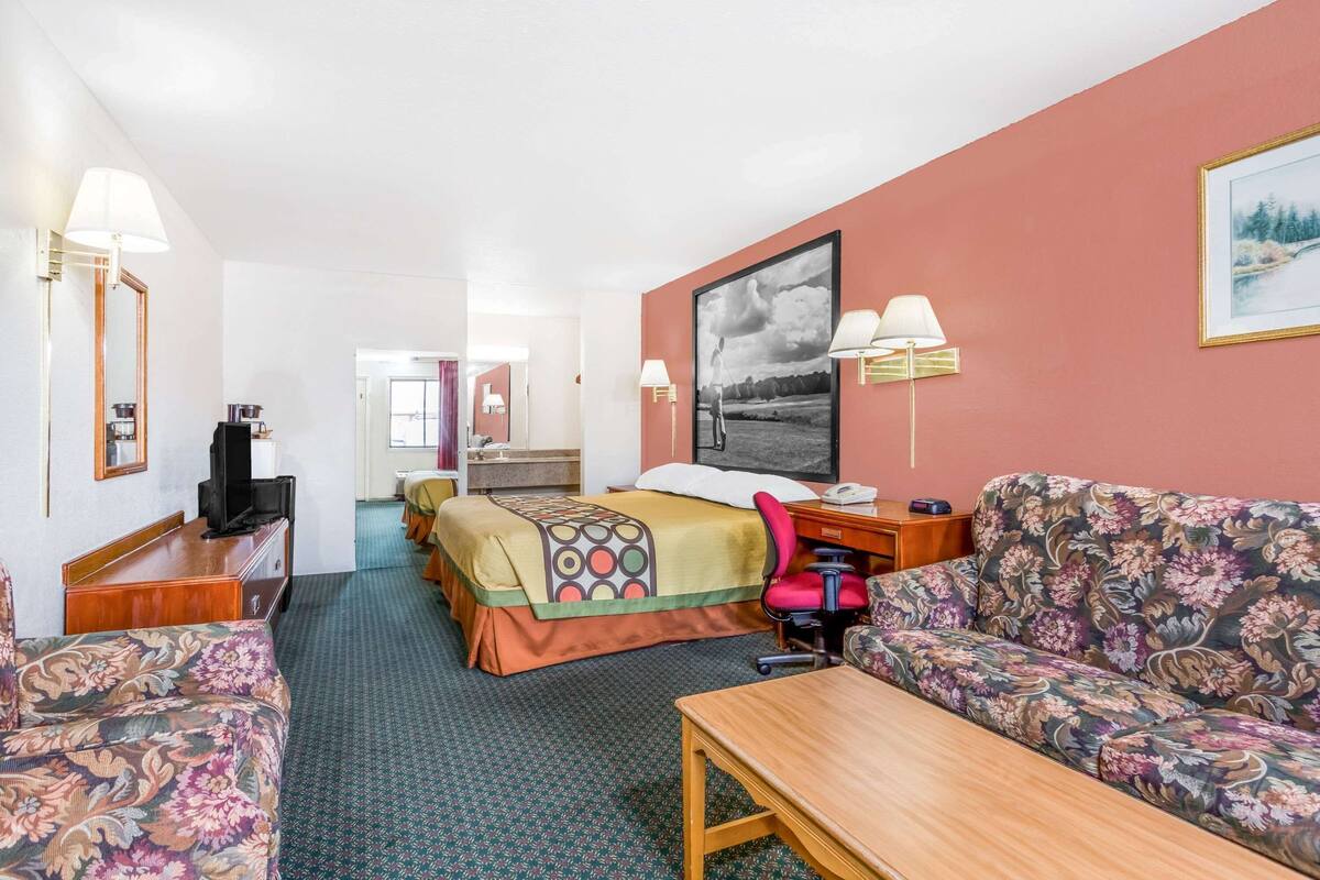 Une chambre d’hôtel comprenant un lit, un canapé, un bureau, une chaise et un téléviseur.