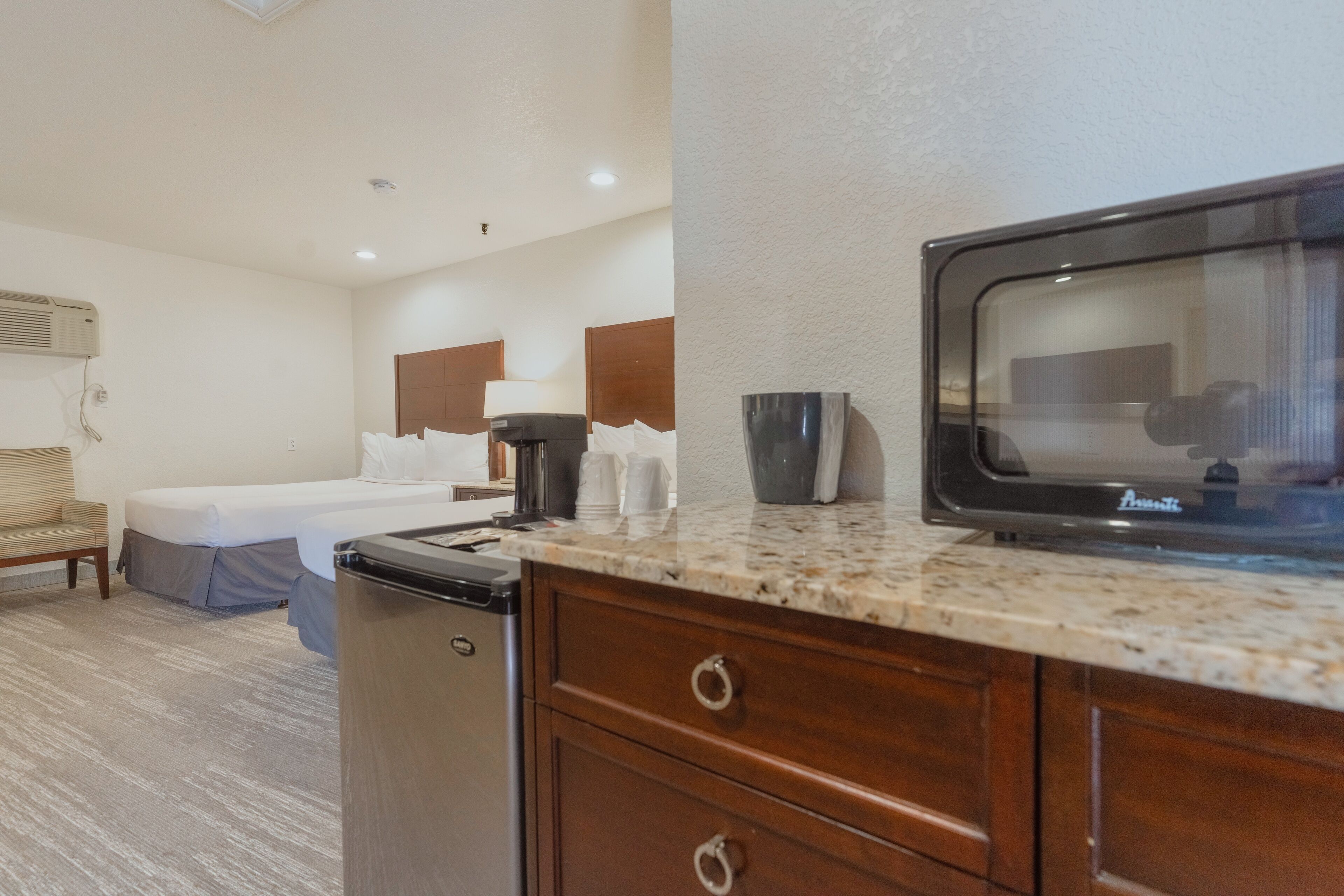 Una habitación de hotel con cama, escritorio, televisión y kitchenette.