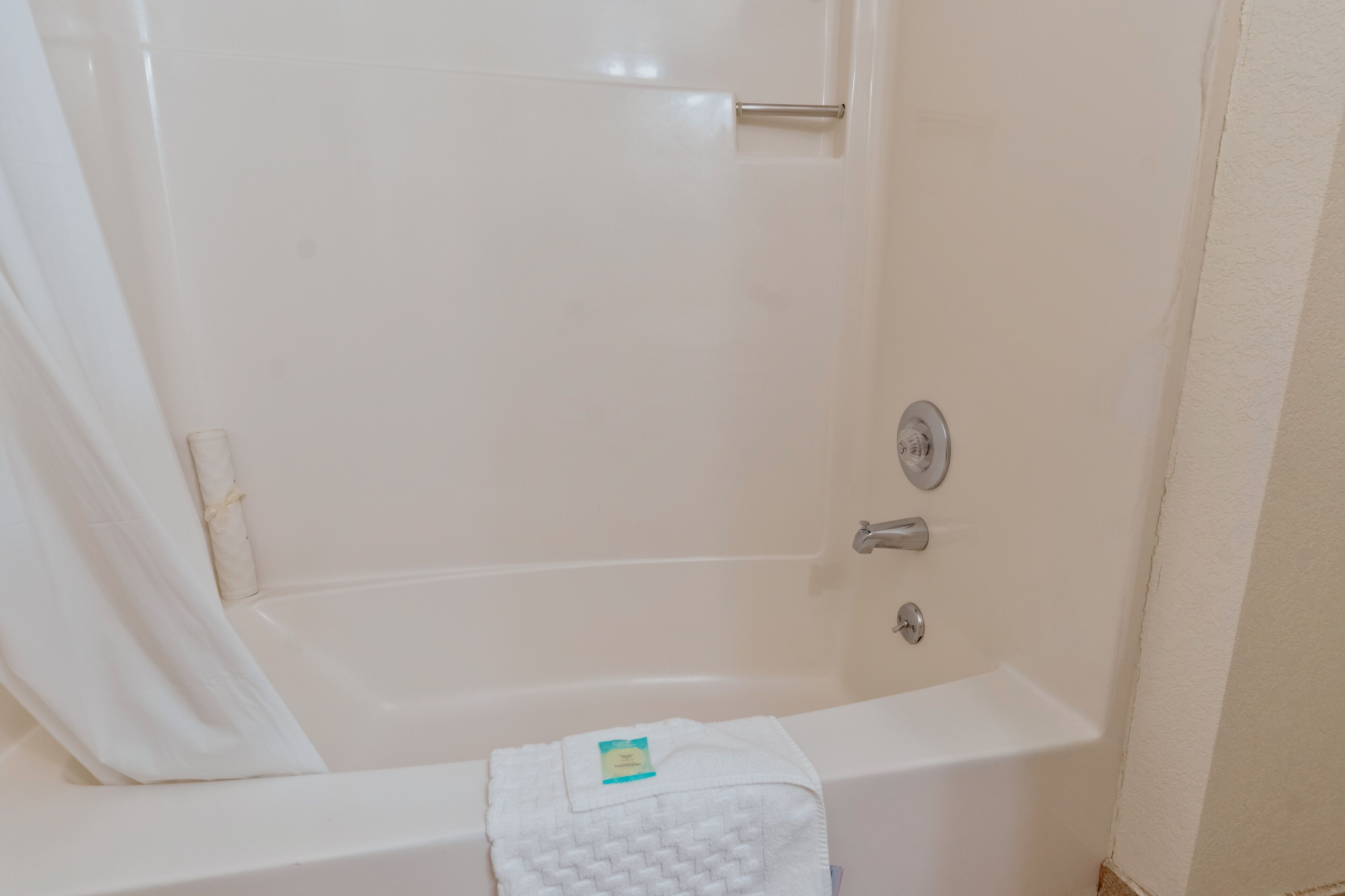 A white bathtub with a towel and a small bottle.