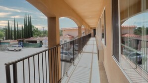 Un balcó cobert amb vista a cotxes aparcats i un edifici amb teulades vermelles.