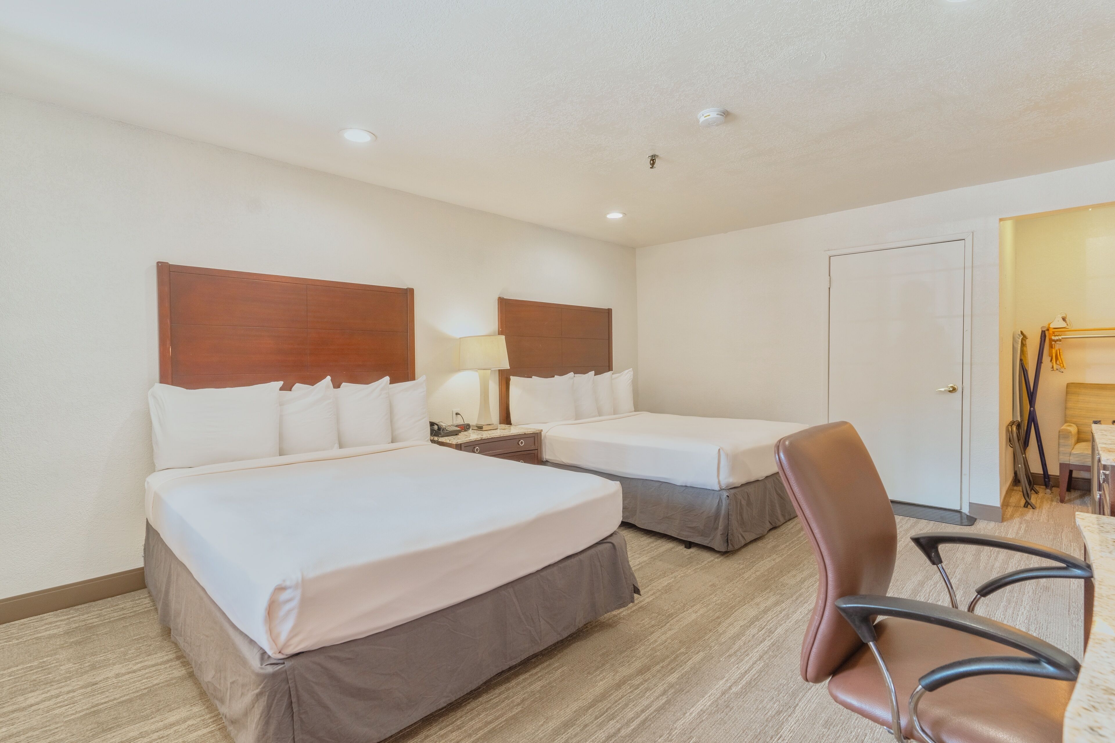 Une chambre d’hôtel avec deux lits, un bureau et une chaise.