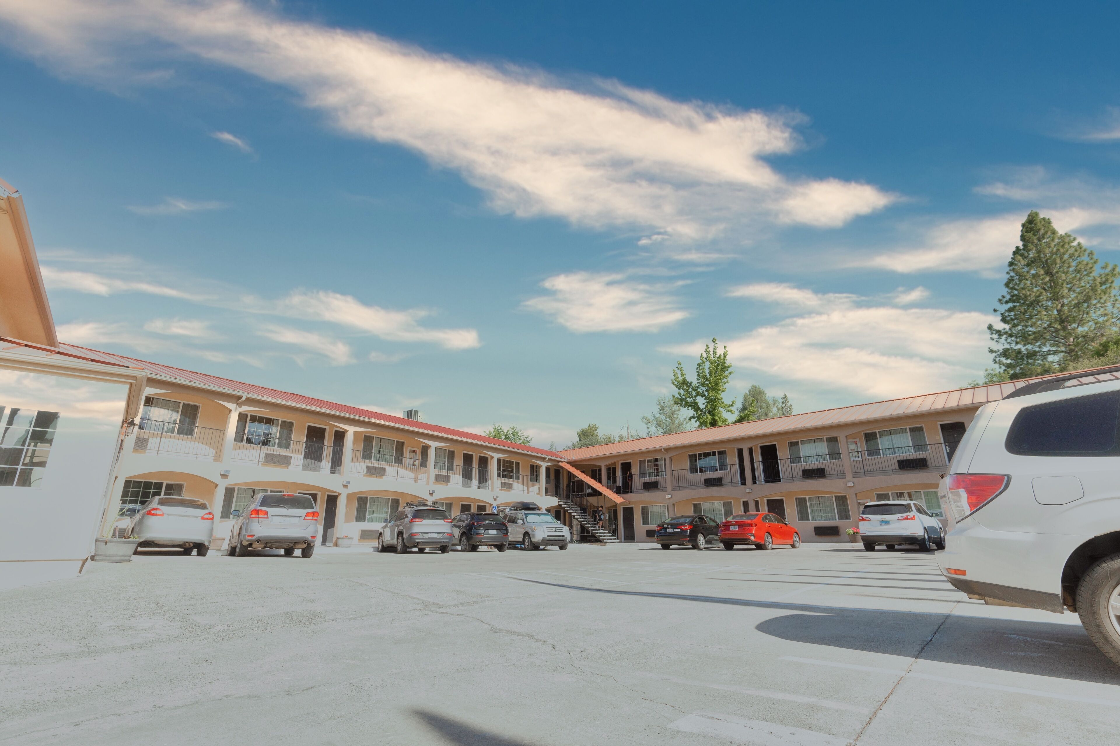 A motel with multiple parking spaces and a central staircase leading to the entrance.