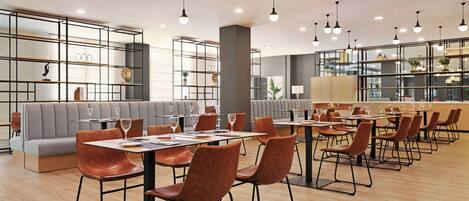 A modern restaurant with high ceilings, pendant lighting, and a mix of seating options including tables and booths.