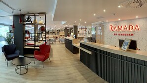 A modern reception area with a marble wall and a sign reading "RAMADA BY WYNDHAM". - Ramada by Wyndham Valencia Almussafes (Almussafes)