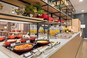 Zona de bufé con diferentes estaciones de comida, que incluyen pasta, ensaladas y fruta.