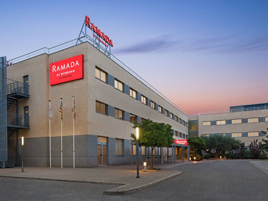 Un edificio moderno con un letrero que dice "RAMADA BY WYNDHAM ALMUSSAPES".