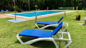 A swimming pool with blue lounge chairs and a lifeguard stand. - Ramada by Wyndham Valencia Almussafes (Almussafes)