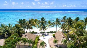 A tropical beach resort with thatched-roof huts, palm trees, and a view of the ocean. - Motu Beachfront Art Villas (Rarotonga)