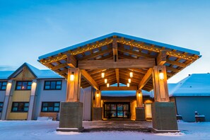 A wooden building with a covered entrance and lights, surrounded by snow. - Prestige Hudson Bay Lodge & Conference Centre, WorldHotels (Smithers)