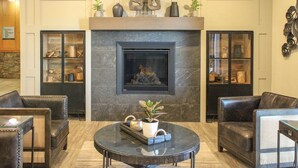 A lobby with a fireplace, leather seating, and a coffee table. - Prestige Hudson Bay Lodge & Conference Centre, WorldHotels (Smithers)