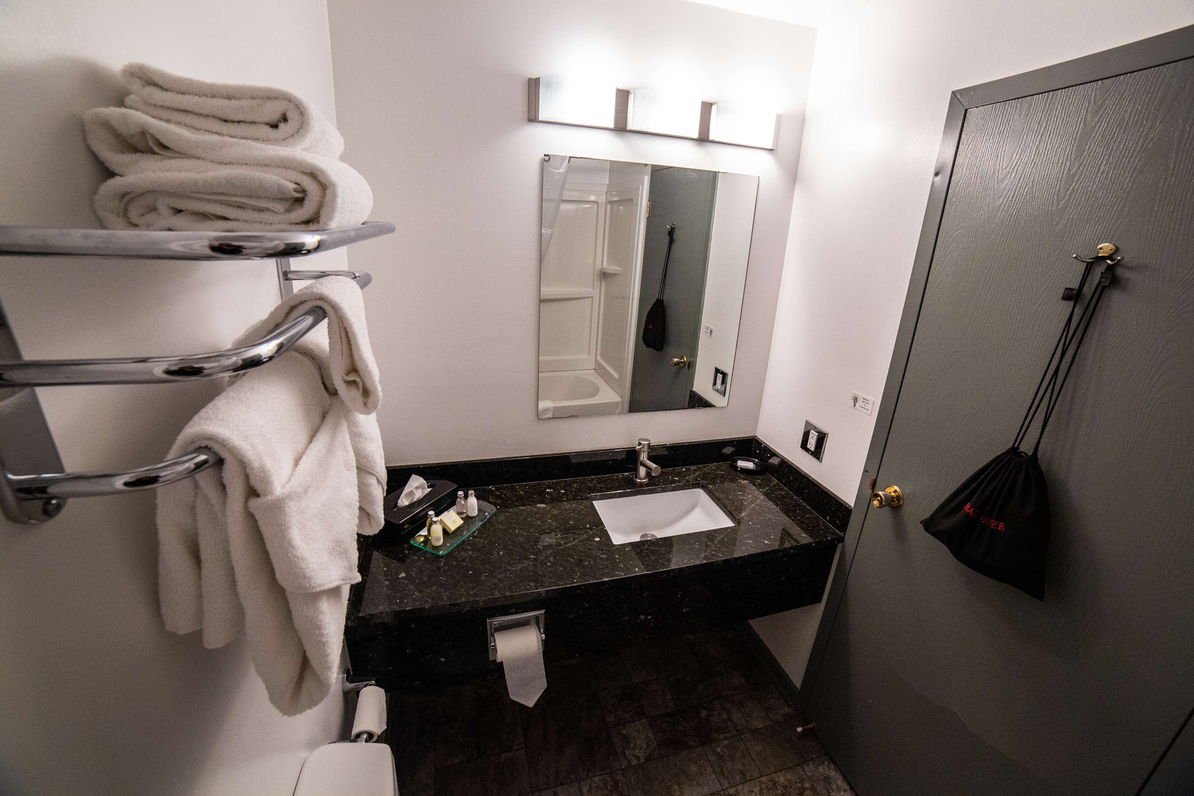 Ein Badezimmer mit Waschbecken, Spiegel, Handtuchhalter und einer Tür mit Griff.