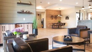 A modern hotel lobby with leather seating, a reception desk, and a dining area. - Prestige Hudson Bay Lodge & Conference Centre, WorldHotels (Smithers)