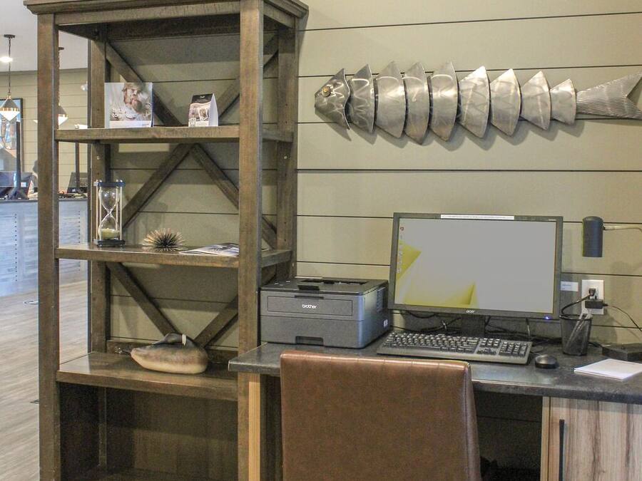 A workspace with a desk, chair, computer, printer, and a decorative wall piece.
