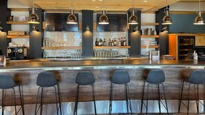 A modern bar area with a wooden bar counter, multiple hanging pendant lights, and bar stools. - Prestige Hudson Bay Lodge & Conference Centre, WorldHotels (Smithers)