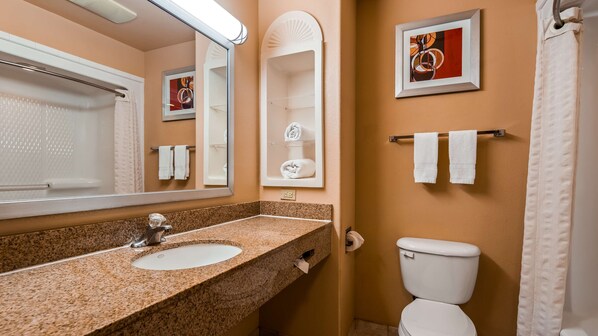 Une salle de bain avec un lavabo à vasque en granit, des toilettes blanches et un tableau abstrait encadré au mur.