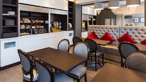 Une cuisine moderne avec un coin repas, comprenant un buffet, un espace détente avec un banc rembourré et un lustre.