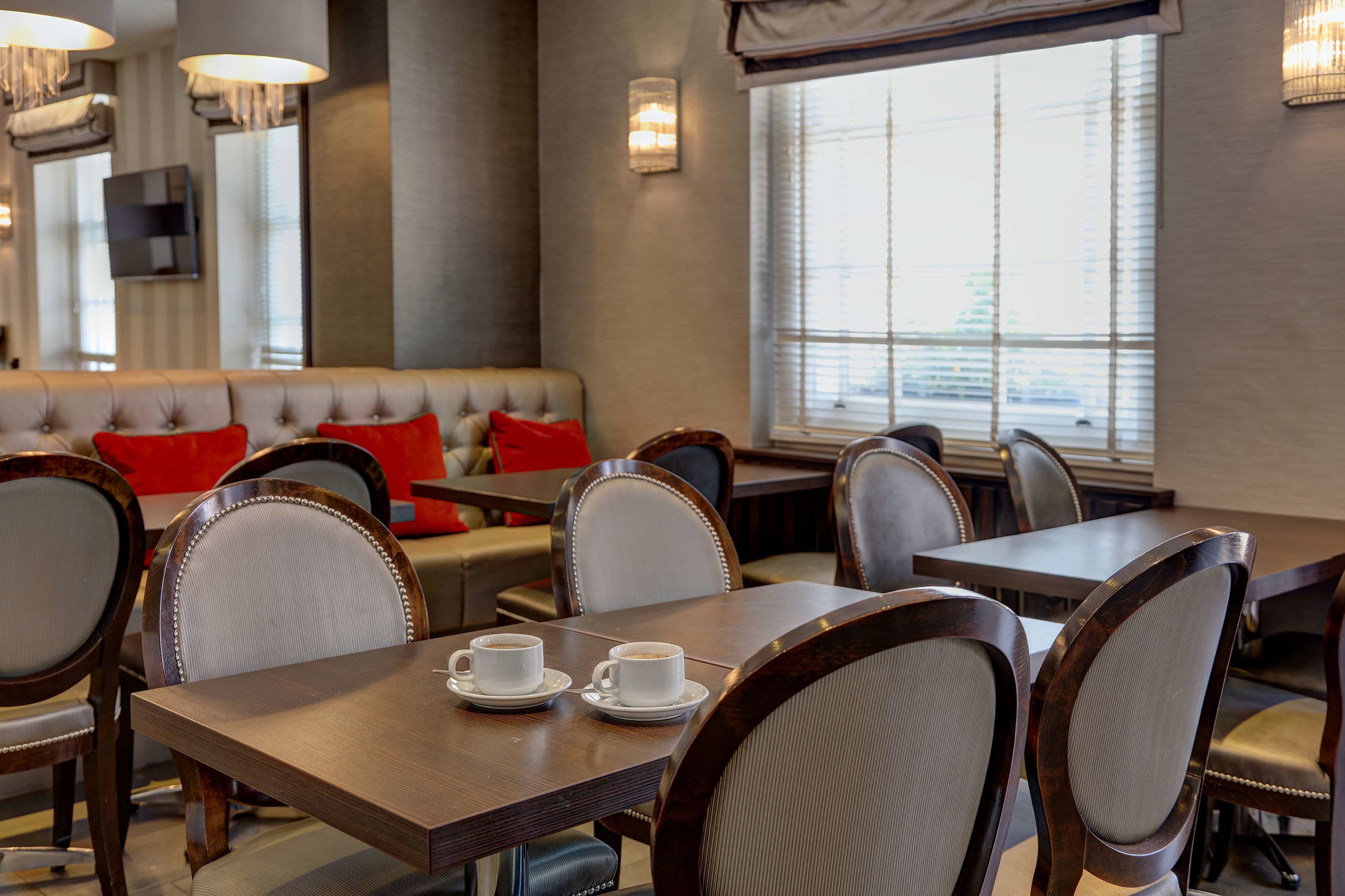Un restaurant avec des banquettes, des tables avec des chaises et une grande fenêtre offrant une vue sur l’extérieur.